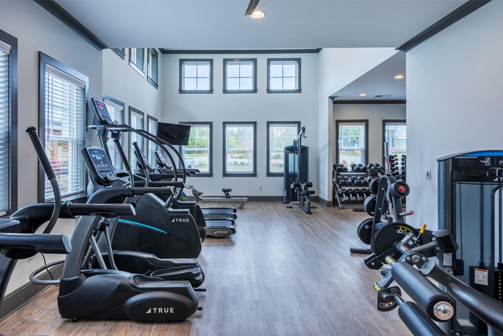 a gym with weights and cardio equipment in a building with windows