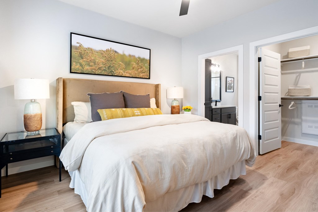A bedroom with a large bed and a painting on the wall.