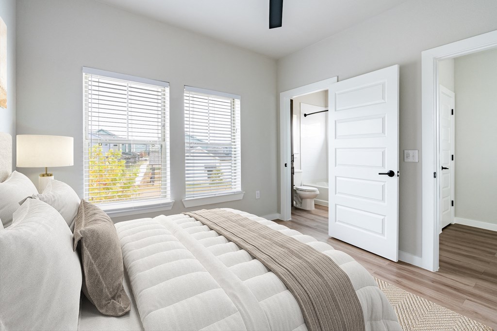 A bedroom with a large bed and a window with blinds.