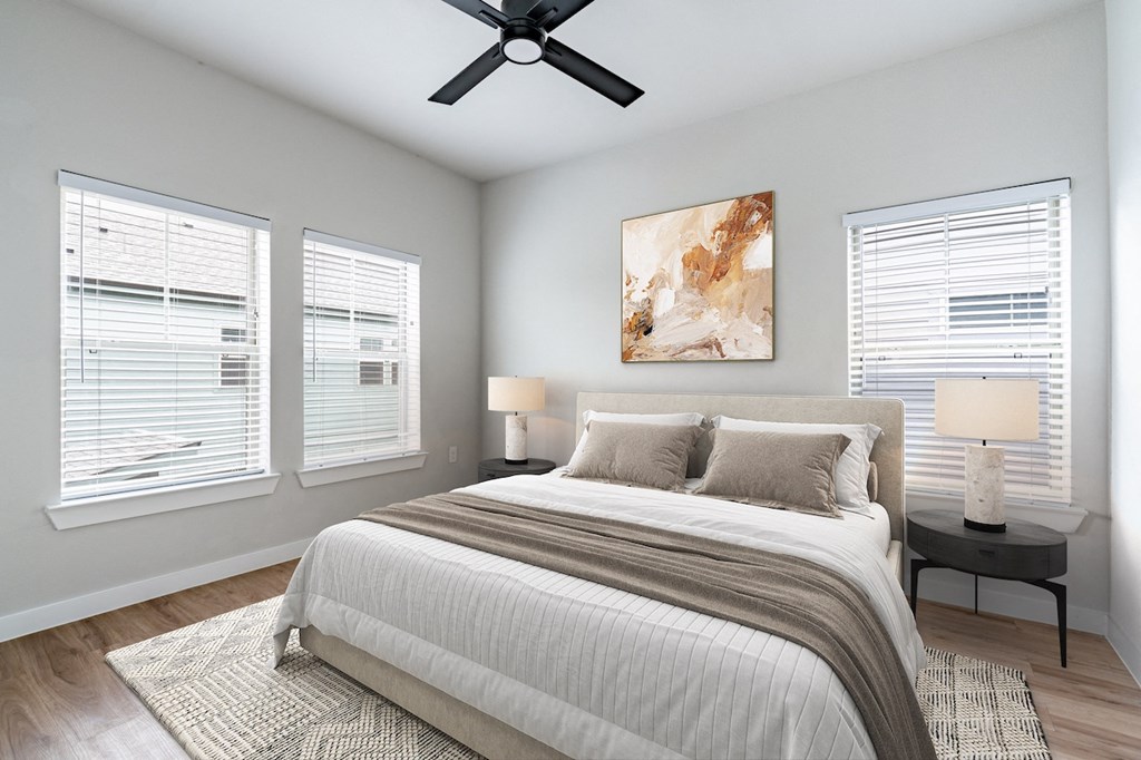 A bedroom with a large bed, a ceiling fan, and two lamps.