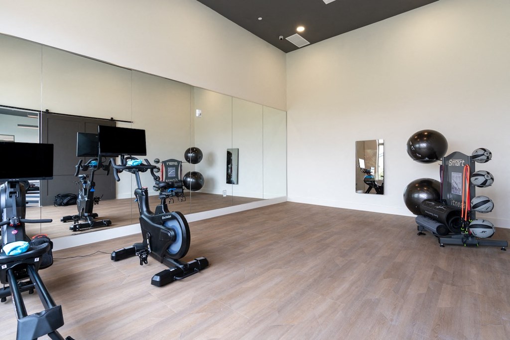 A gym with exercise equipment and mirrors on the wall.