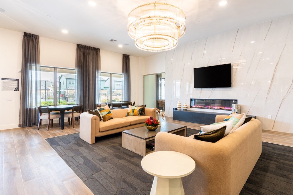 A modern living room with a large couch, a coffee table, and a flat-screen TV mounted on the wall.