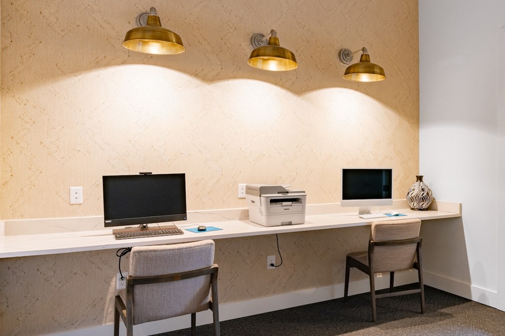 Two desks with computers and printers on them.