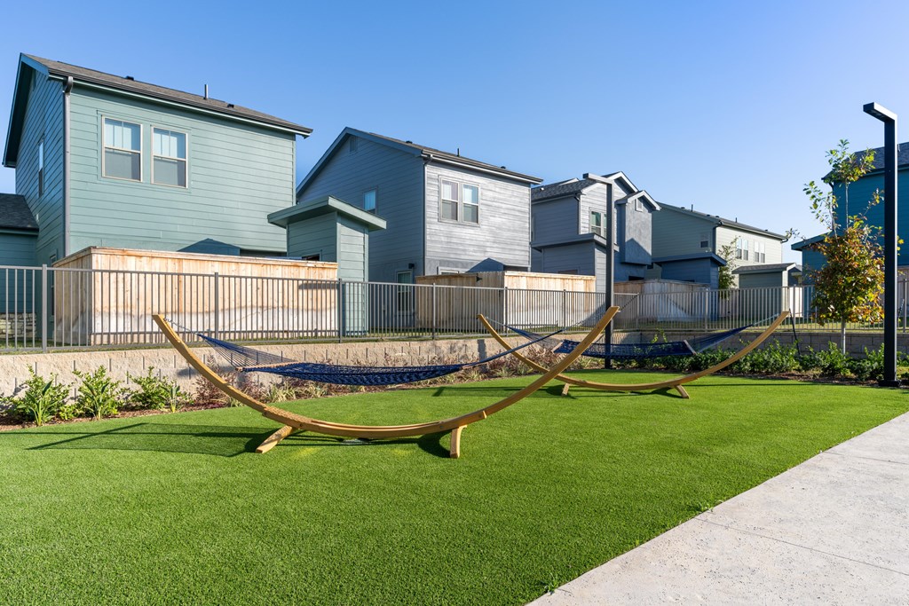 A sculpture sits in the grass in front of a row of houses.