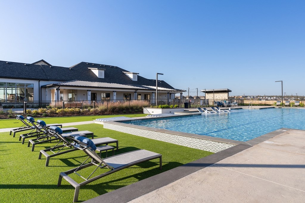 A pool with sun loungers in front of a building.