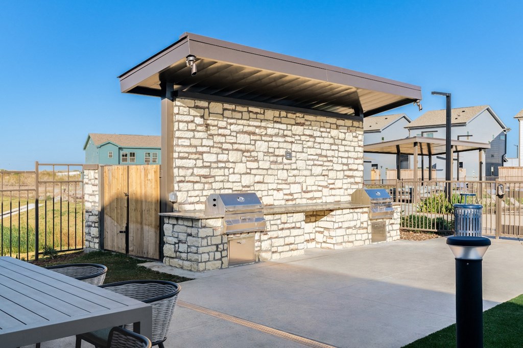 A stone building with a brown roof and a black fence.