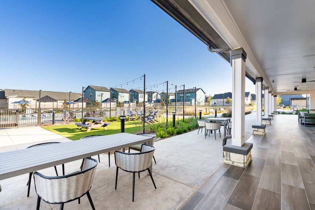 A patio with tables and chairs is shown with a view of a residential area in the background.