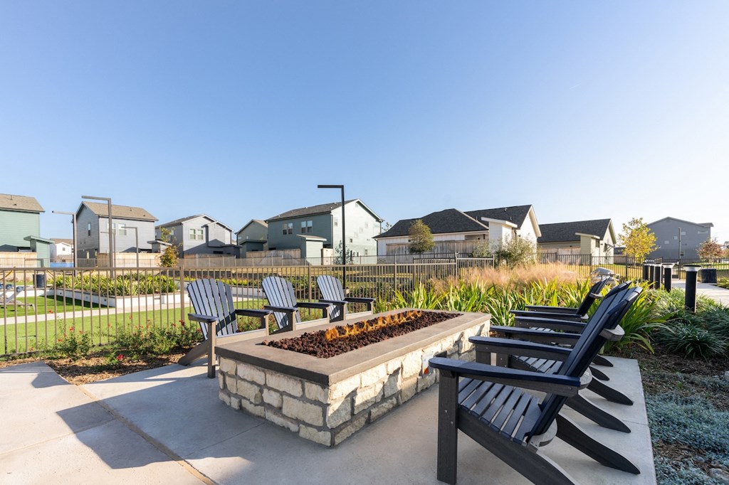 A park bench with a stone base and a fire pit in the middle.