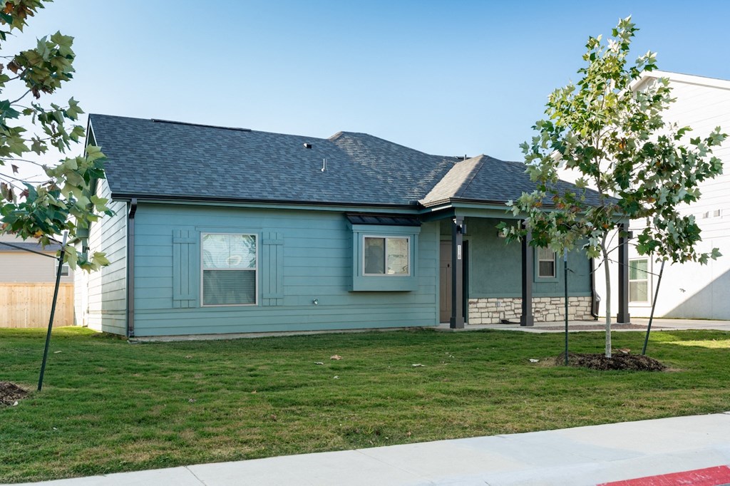 A blue house with a grey roof and a white fence.