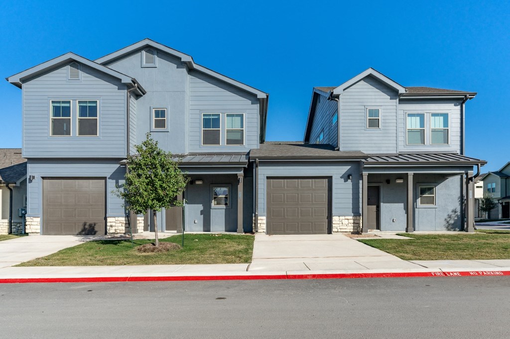 A two-story house with a garage on the first floor and a balcony on the second floor.