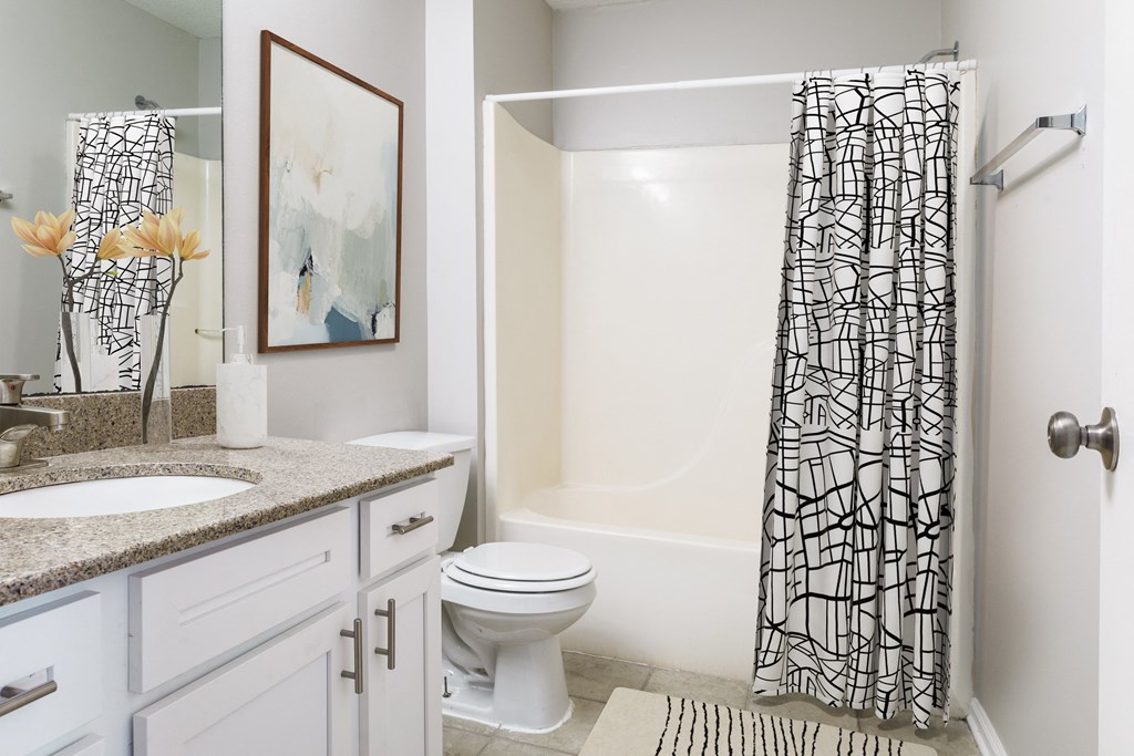 a bathroom with a white toilet next to a bathtub with a shower curtain