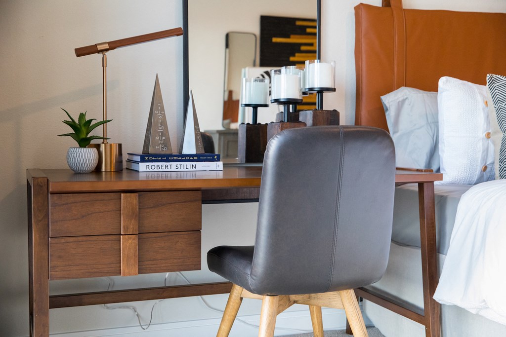 A brown leather chair sits in front of a wooden desk in a bedroom at 27Seventy Lower Heights apartments in Houston, TX.
