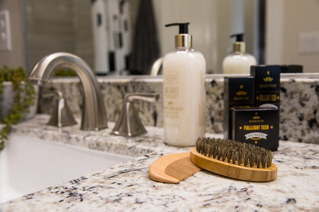A bathroom sink with a brush and two bottles of soap at 27Seventy Lower Heights apartments in Houston, TX.