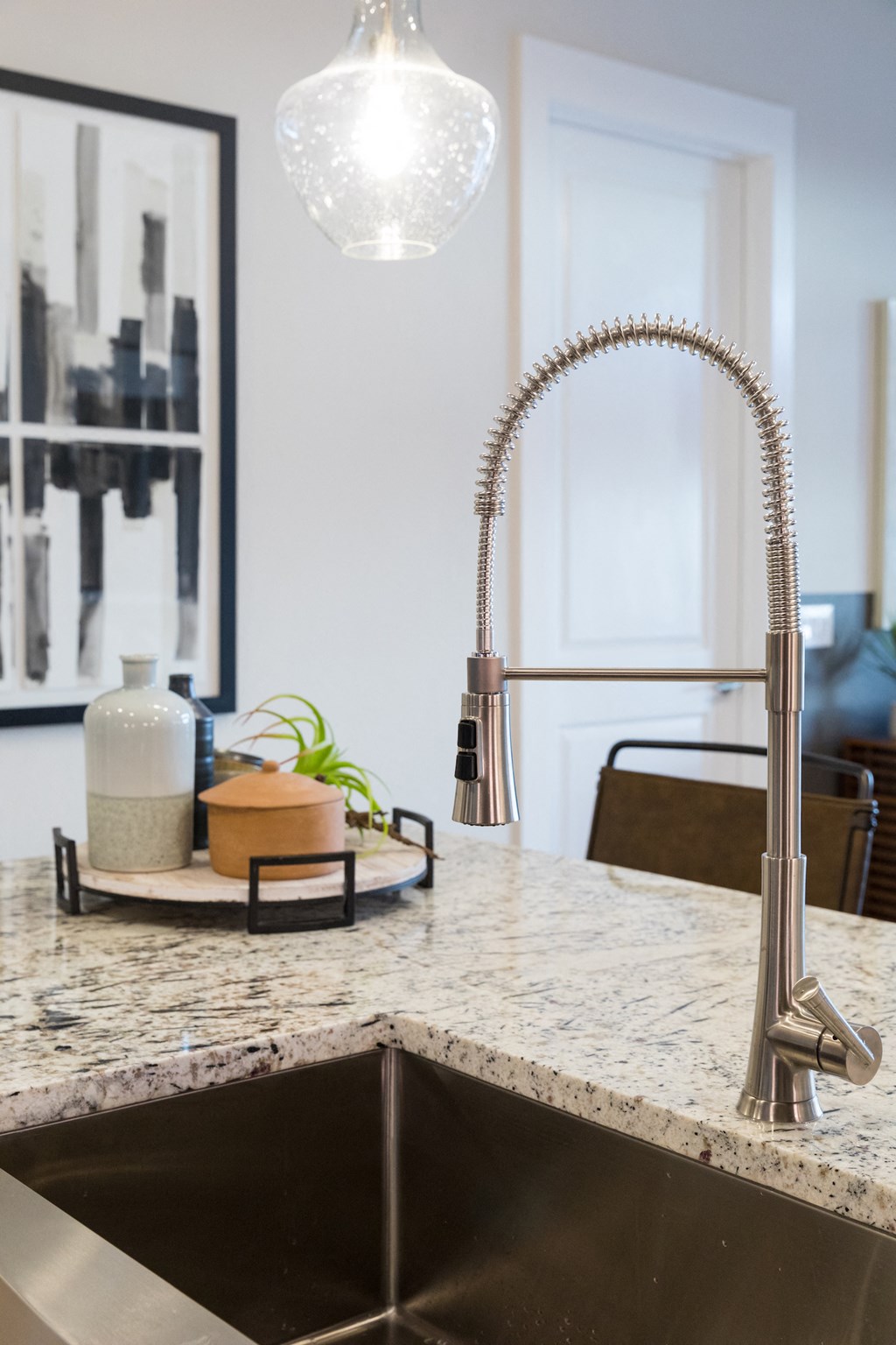A kitchen sink with a chrome faucet and a plant on the counter at 27Seventy Lower Heights apartments in Houston, TX.