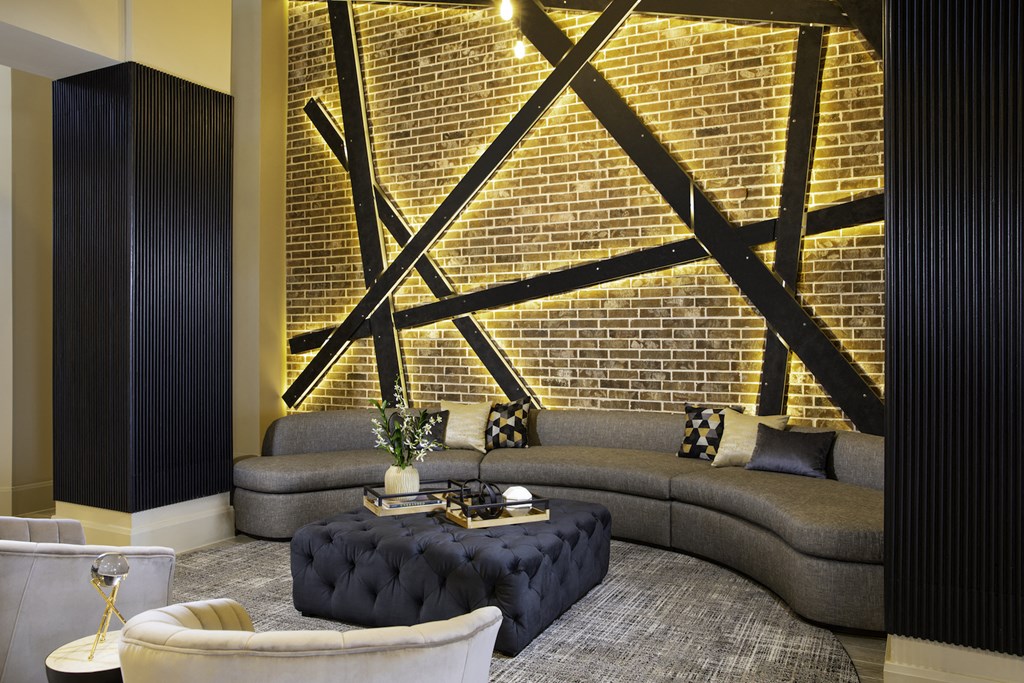 A modern clubhouse with a grey sofa and a black ottoman at 27Seventy Lower Heights apartments in Houston, TX.