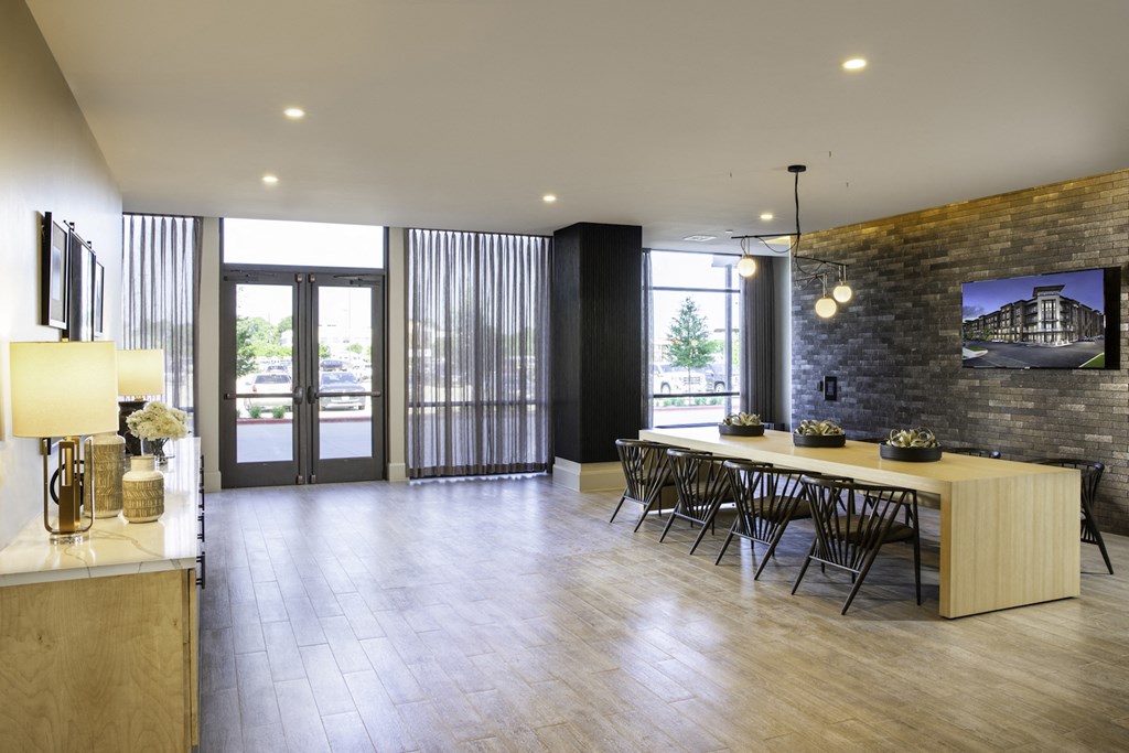 A modern clubhouse with a long table and chairs at 27Seventy Lower Heights apartments in Houston, TX.