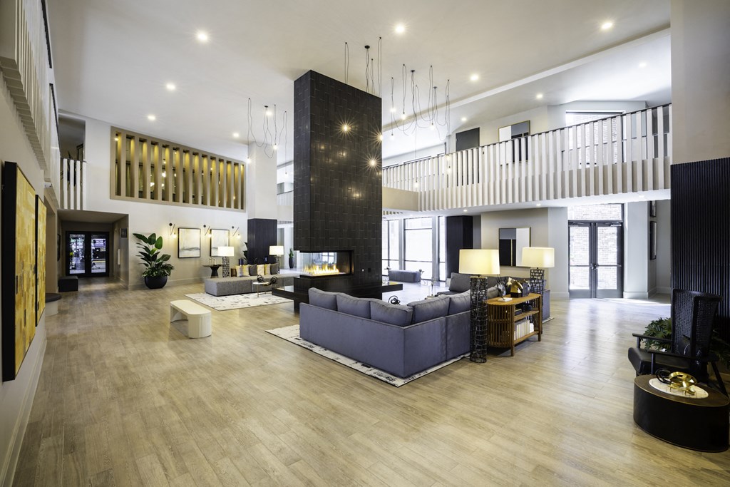 A spacious clubhouse with a grey sofa set and a wooden floor at 27Seventy Lower Heights apartments in Houston, TX.