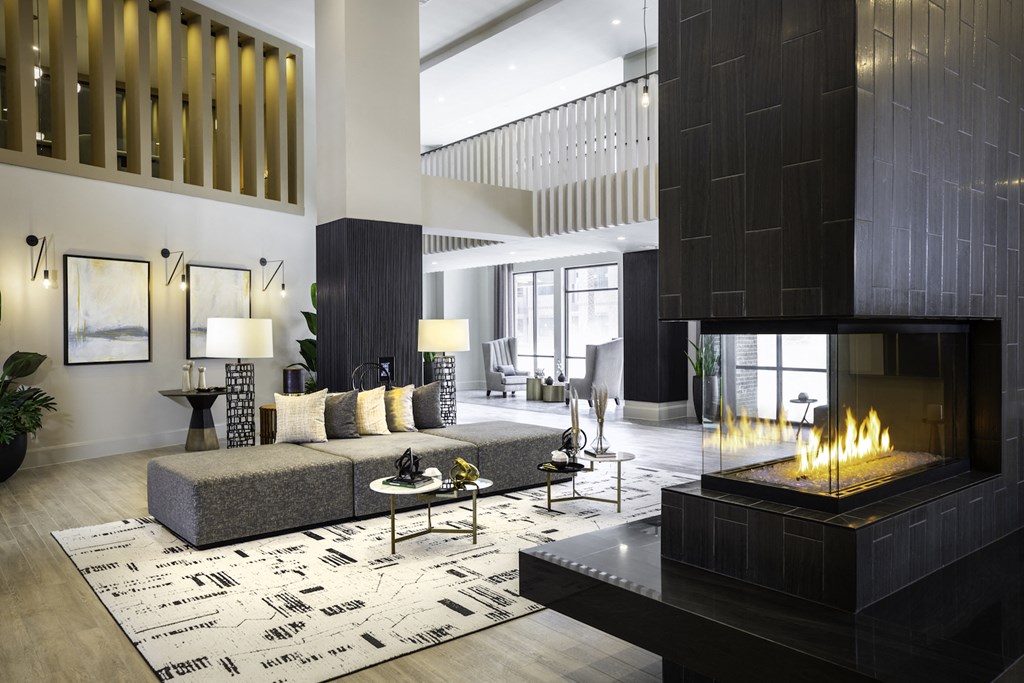 A modern clubhouse with a fireplace and a grey sofa at 27Seventy Lower Heights apartments in Houston, TX.