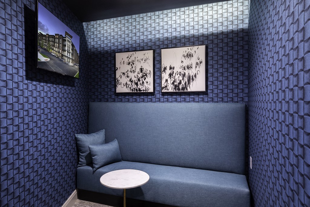 A blue couch with a white table in front of it and two pictures on the wall at 27Seventy Lower Heights apartments in Houston, TX.