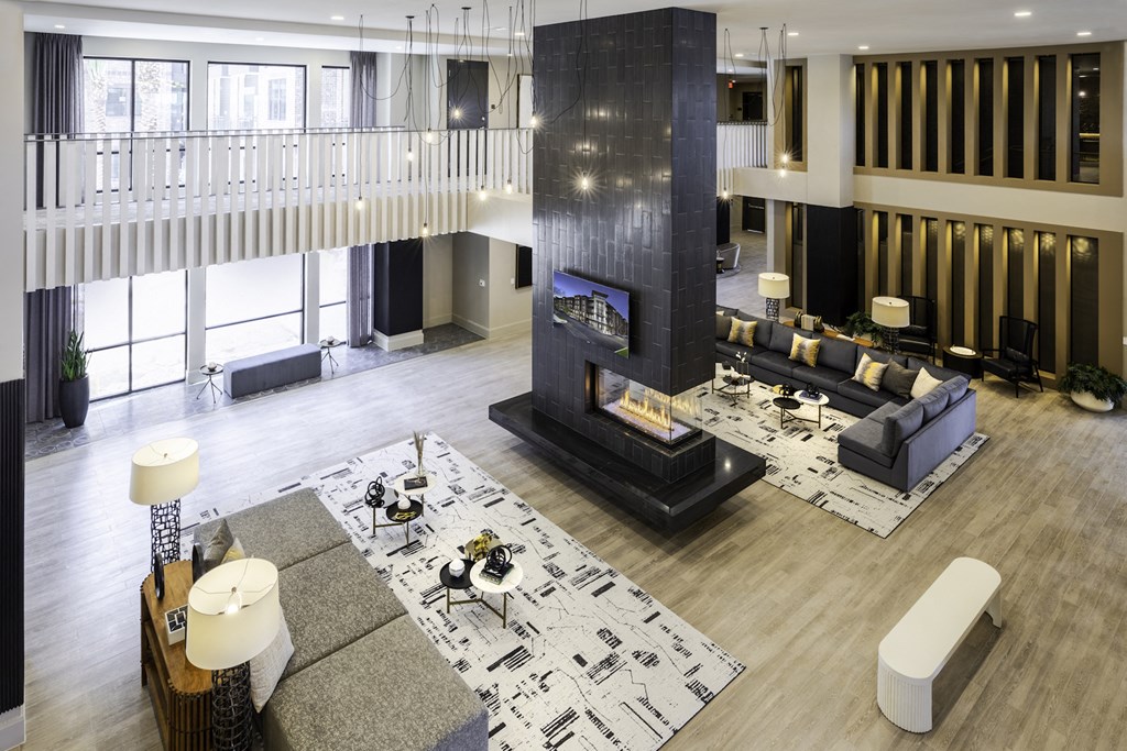 A modern clubhouse with a fireplace and a large rug at 27Seventy Lower Heights apartments in Houston, TX.
