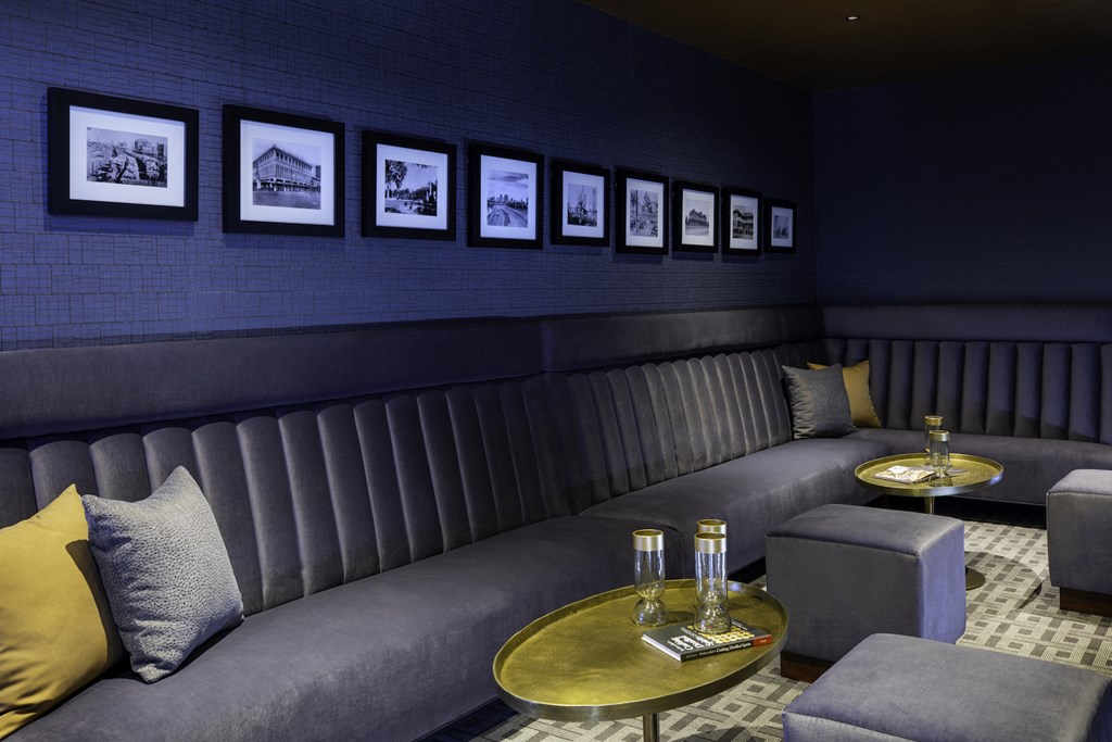 A cozy room with a grey sofa, a gold coffee table, and pictures on the wall at 27Seventy Lower Heights apartments in Houston, TX.
