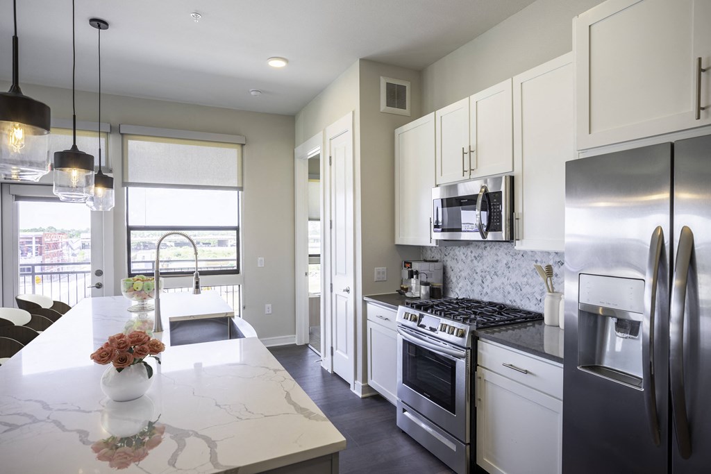 A modern kitchen with stainless steel appliances and a marble style island at 27Seventy Lower Heights apartments in Houston, TX.