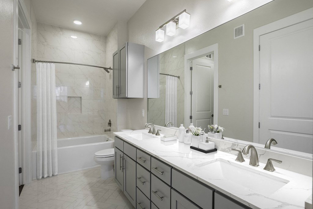 A bathroom with a marble style shower and tub  combo and sink at 27Seventy Lower Heights apartments in Houston, TX.