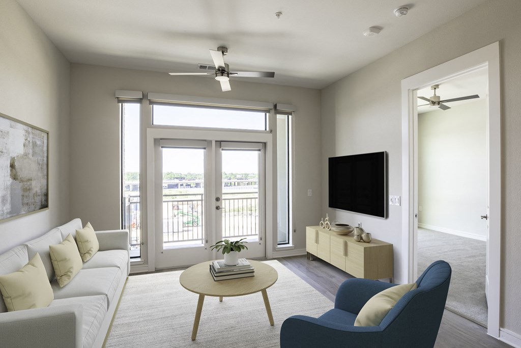 A living room with a white couch, a blue armchair, a coffee table, and a flat-screen TV at 27Seventy Lower Heights apartments in Houston, TX.