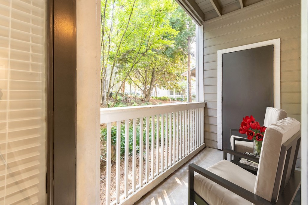 a balcony with a chair and a vase of flowers
