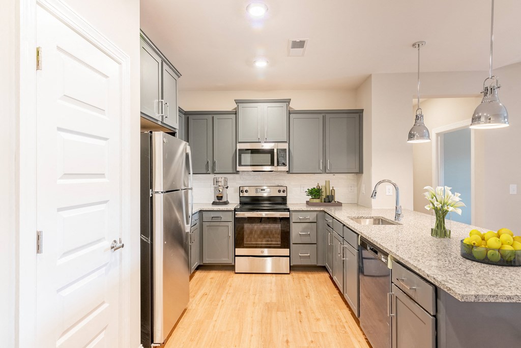 a large kitchen with stainless steel appliances and gray cabinets