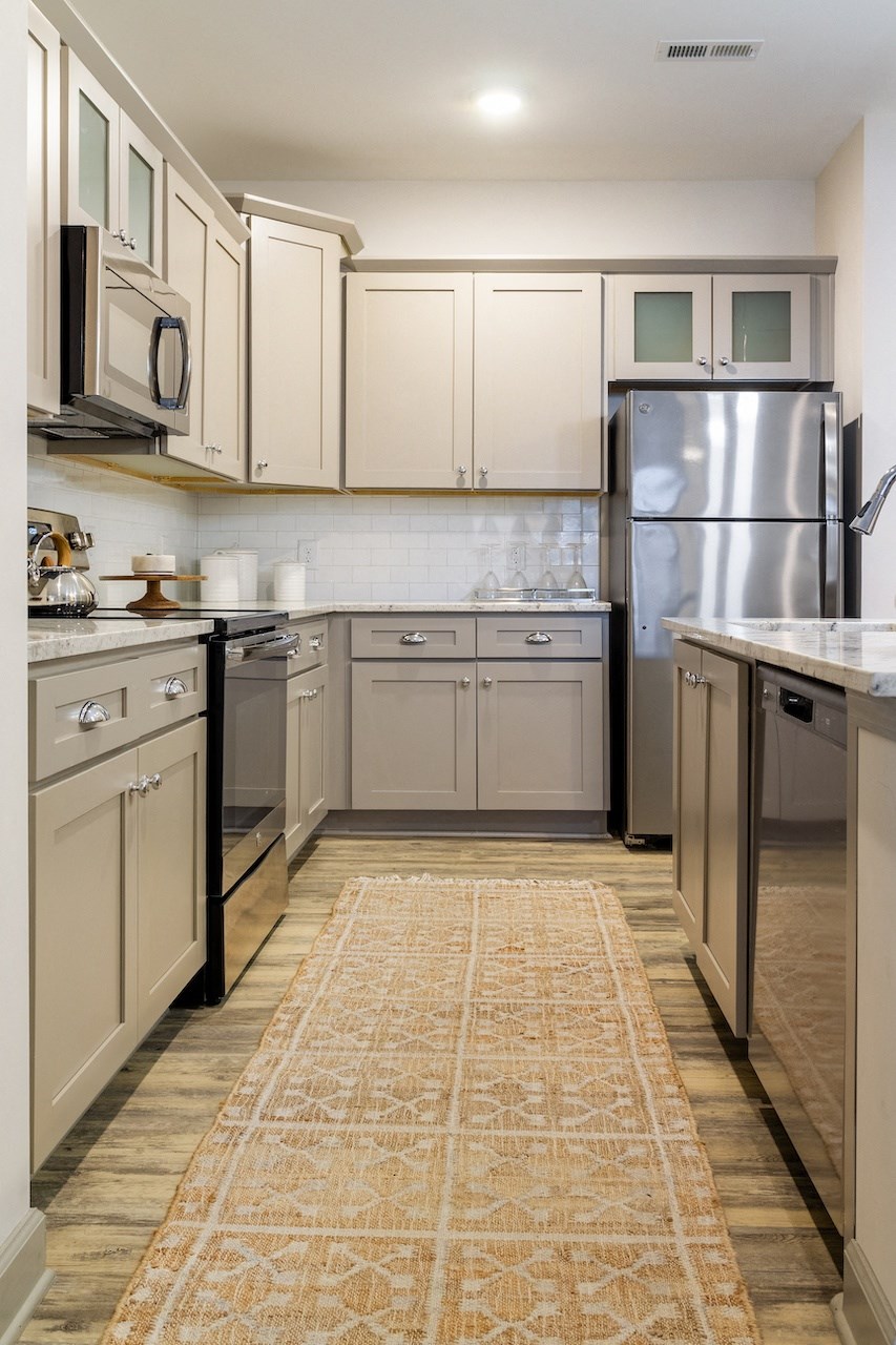 A kitchen with a rug on the floor and a refrigerator on the right.