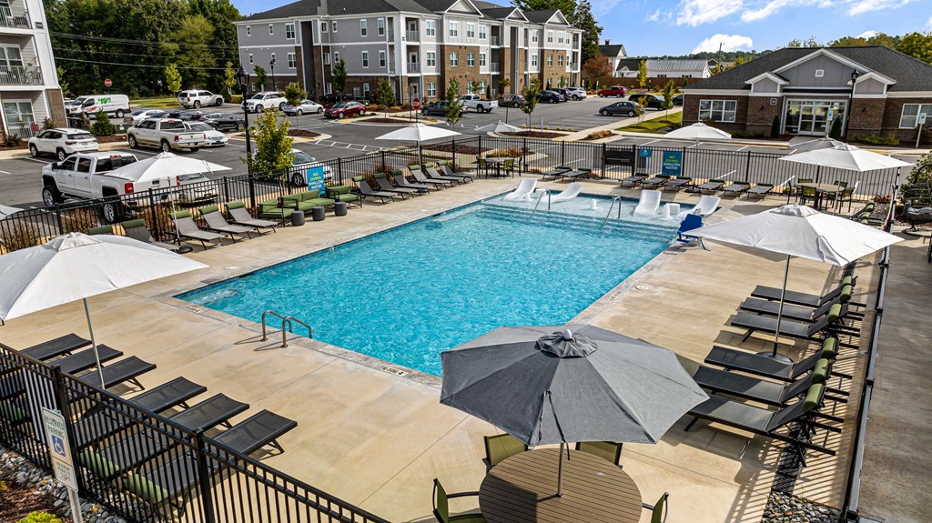 a swimming pool with chairs and umbrellas at the resort on a sunny day