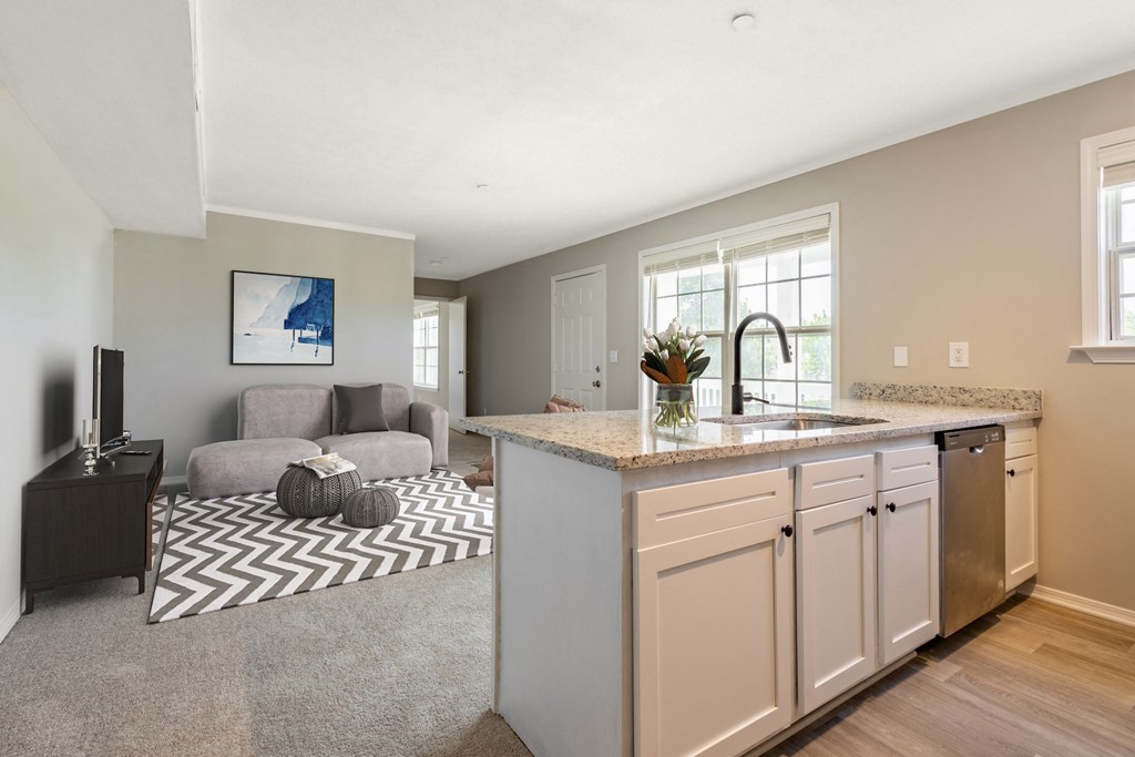 a kitchen with an island and a living room in the background
