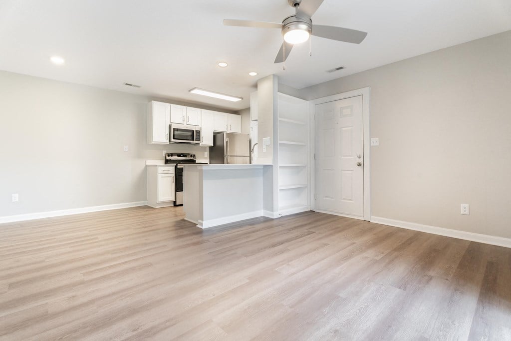 an empty living room and kitchen with a ceiling fan