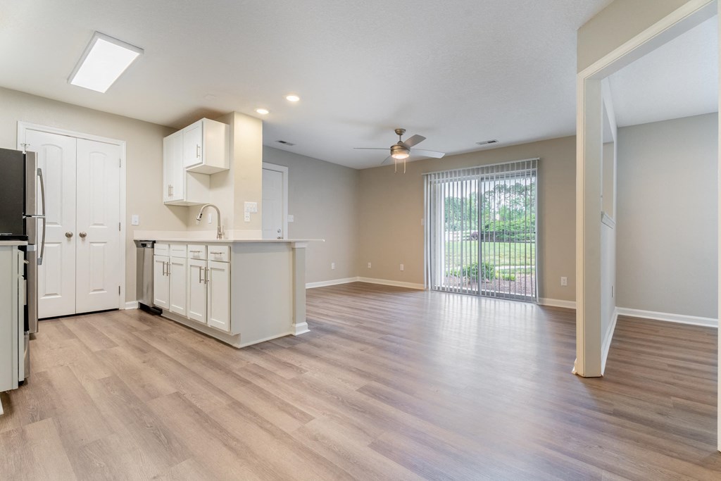 an open kitchen and living room with a sliding glass door to a balcony
