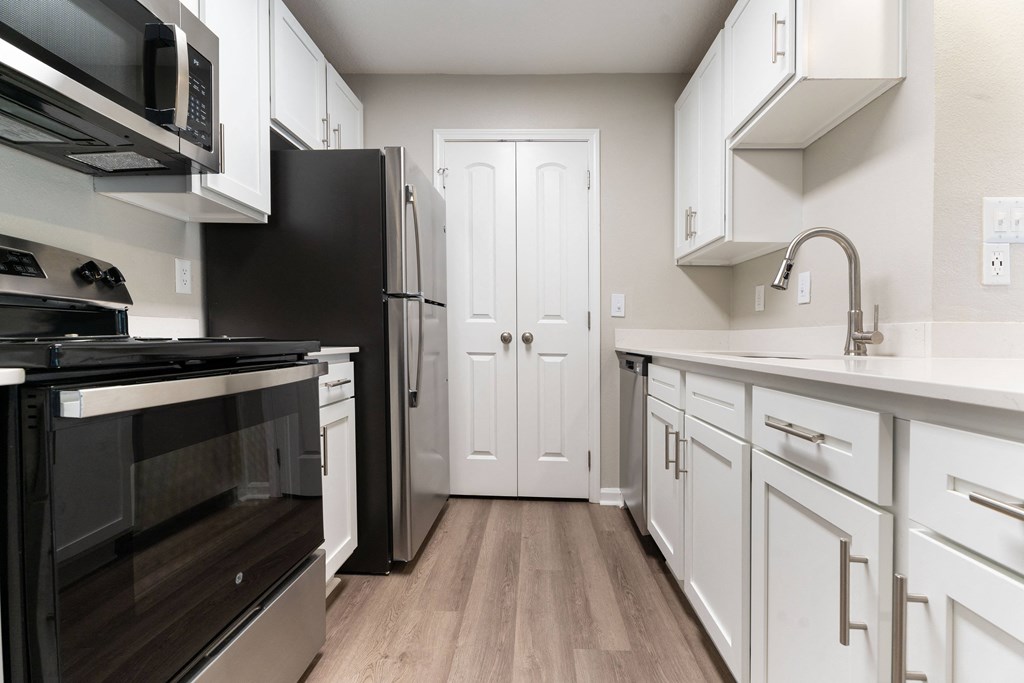 an empty kitchen with white cabinets and stainless steel appliances