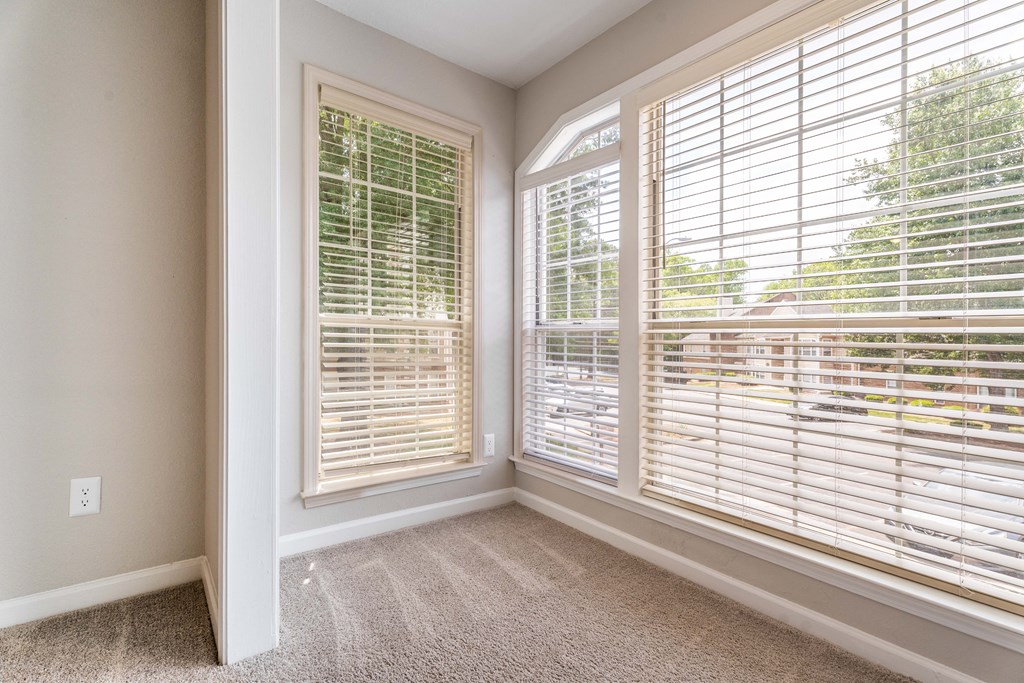 an empty living room with large windows and blinds