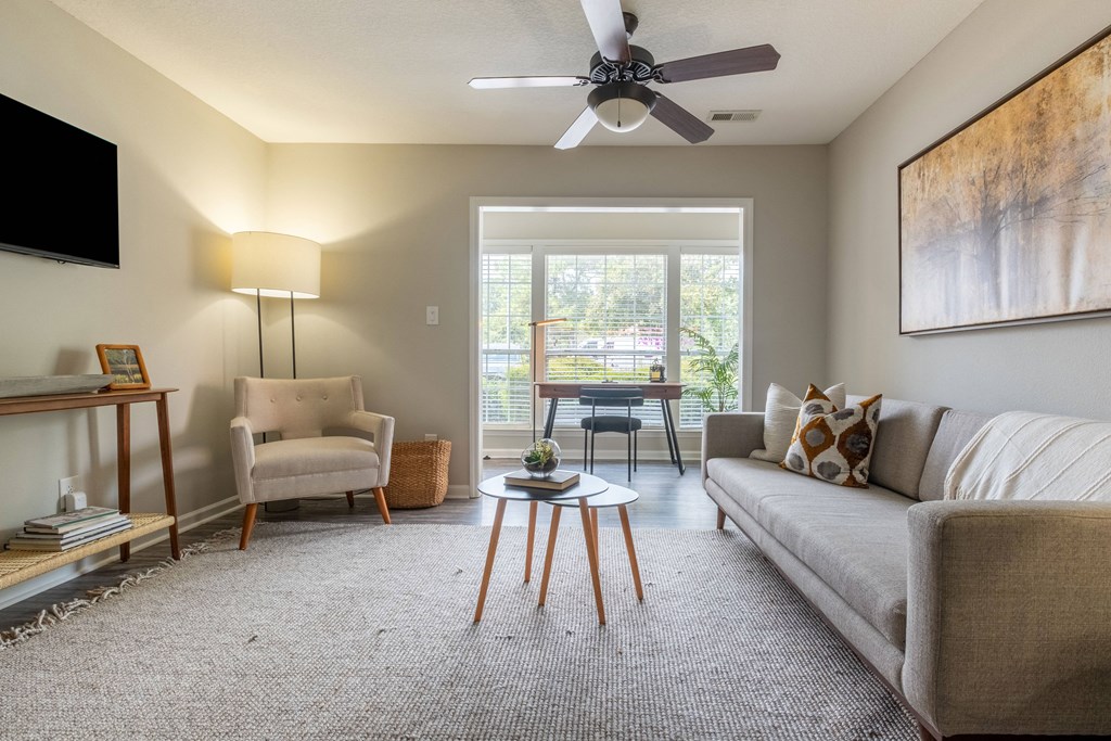a living room with a ceiling fan and a large window