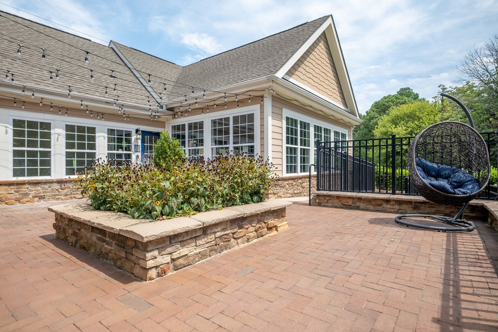 a patio with a seating area and a swing in front of a house
