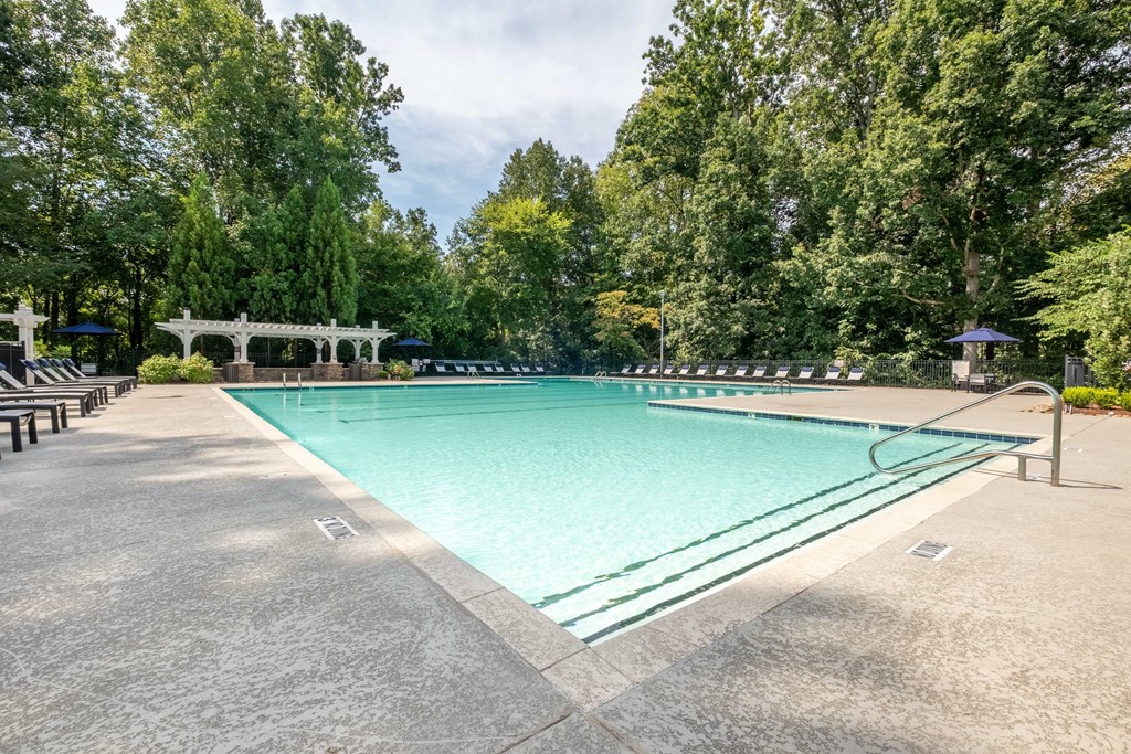 a large swimming pool with trees in the background
