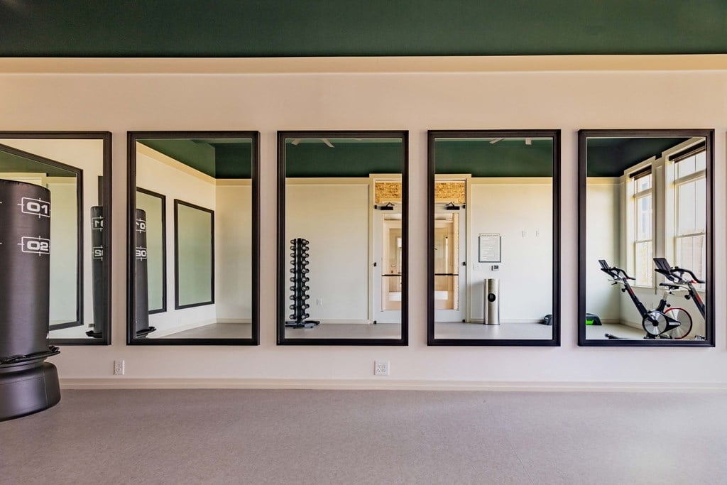 a fitness room with five large mirrors on the wall
