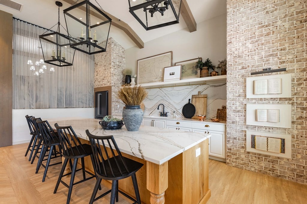 a kitchen with a white marble counter top and a brick wall