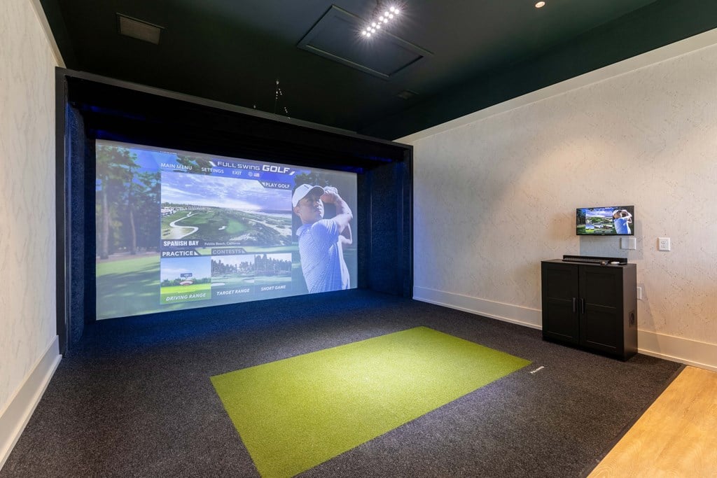 a room with a projector screen and a green carpet