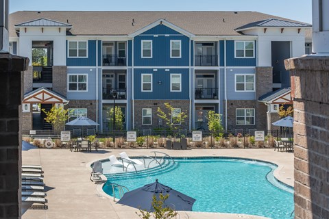 A large blue and white apartment building with a pool in the foreground.