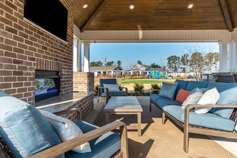 a covered porch with couches and chairs and a fireplace
