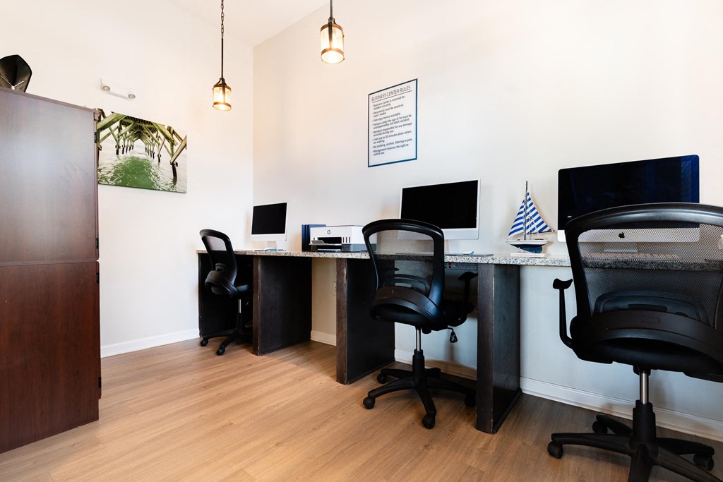 two desks with computers and chairs in an office