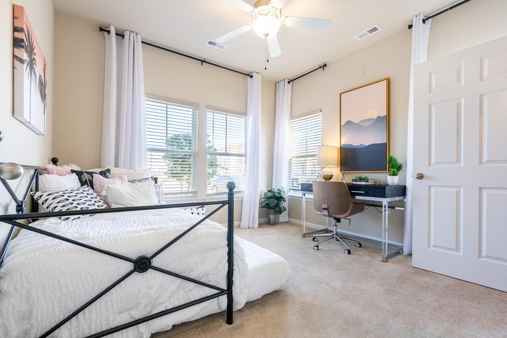 an open bedroom with a bed and a desk with a window