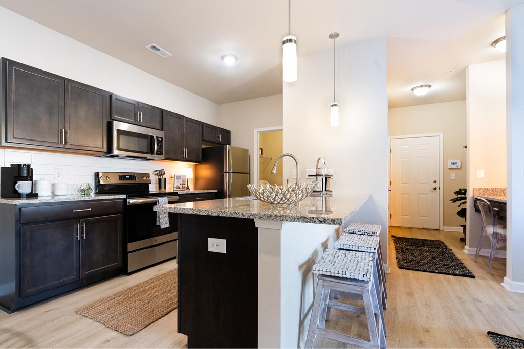 a large kitchen with black cabinets and a bar with stools