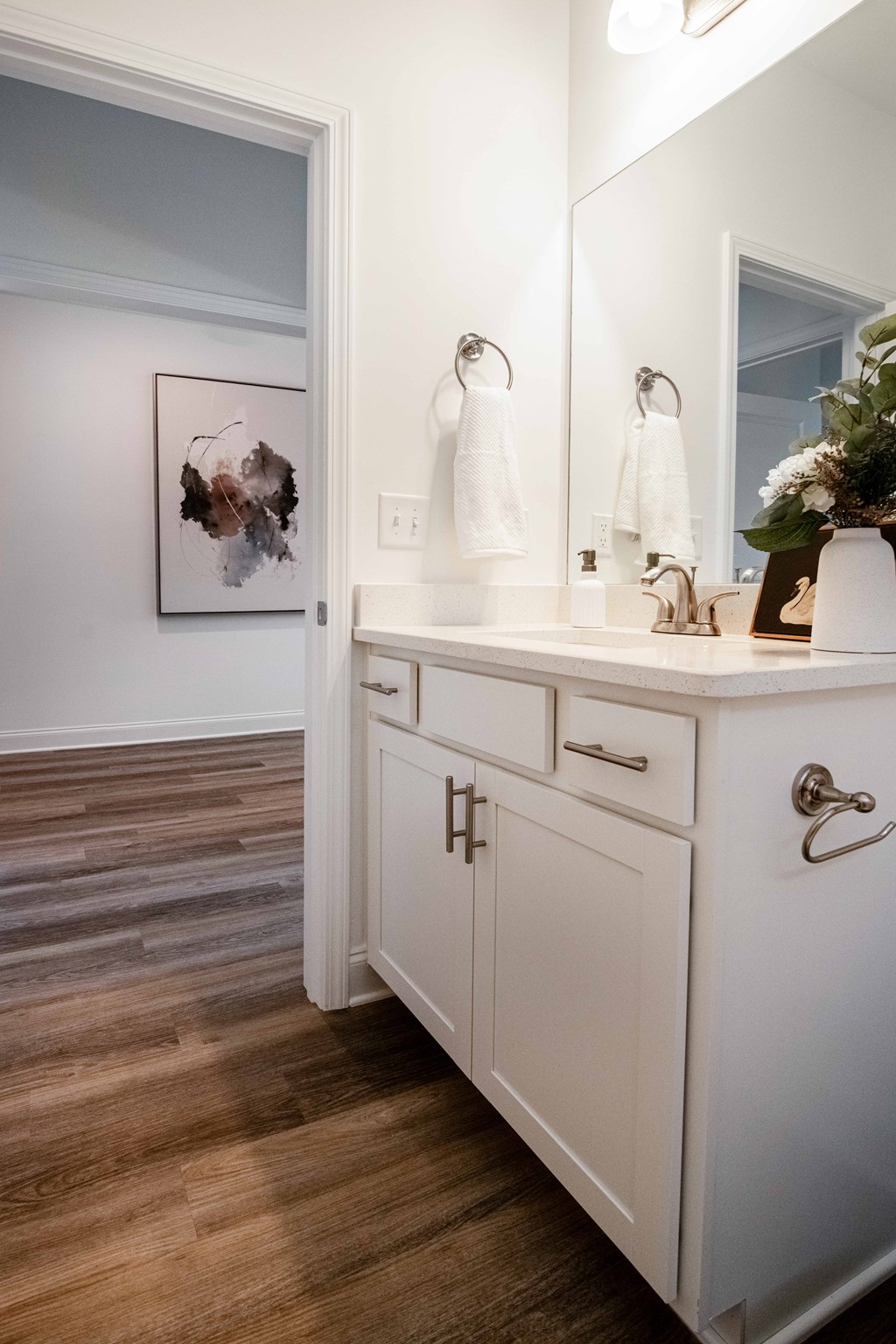A bathroom with a white cabinet and a painting on the wall.
