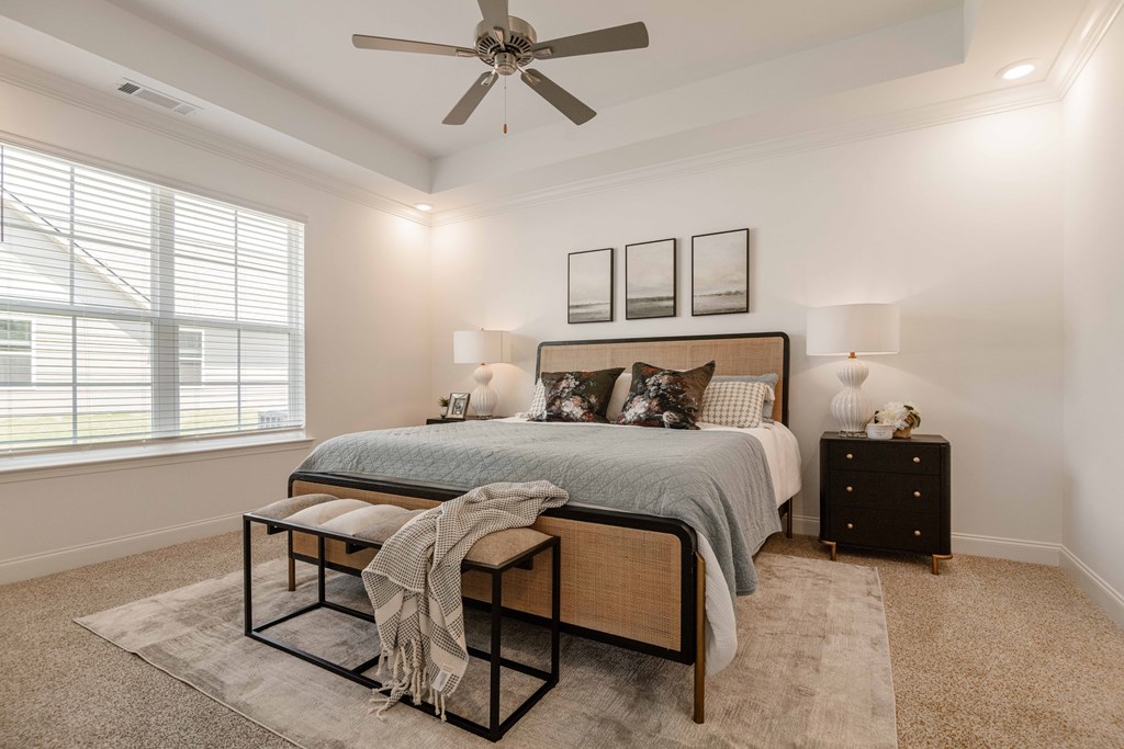 A bedroom with a bed, nightstand, and a ceiling fan.